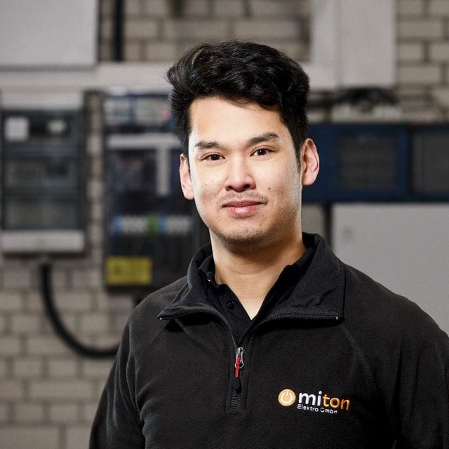Porträt eines der beiden Geschäftsführer von Miton Elektro in Arbeitskleidung vor einer Verteilung.