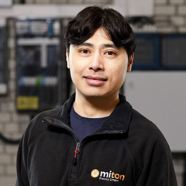 Porträt des zweiten Geschäftsführers von Miton Elektro in Arbeitskleidung vor einer Verteilung.