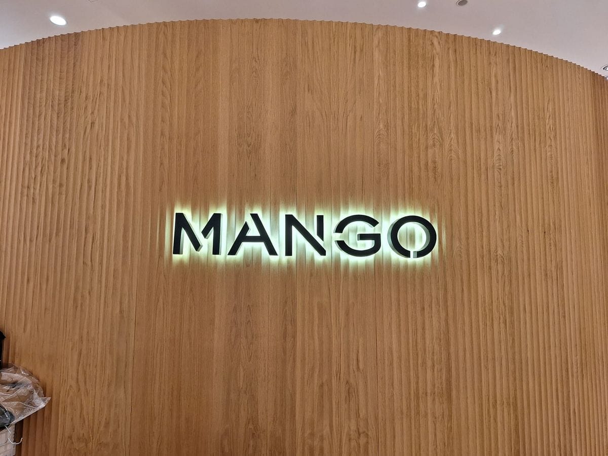 Hinterleuchteter Mango-Schriftzug auf einer Holzwand, installiert von Miton Elektro.